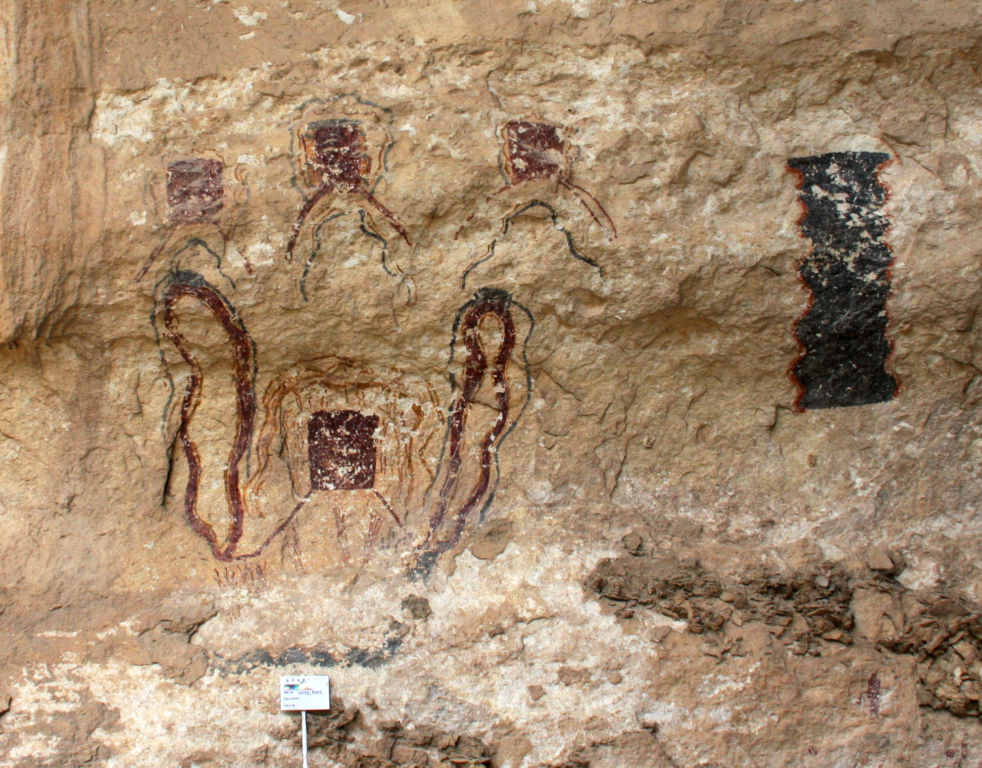 This is an example of many enigmatic figures together. There are four boxes with legs and several serpentine arches surrounding these elements. There is also a large crenulated shape on the right.