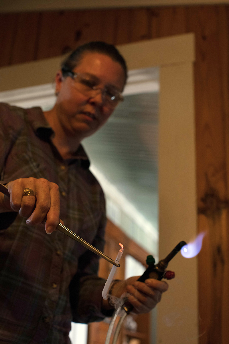 Karen using an oxygen/propane torch to seal a glass a carbon dioxide sample for AMS radiocarbon dating.