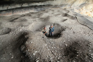 Charles discusses the deposit layers with James while they site in the middle of the massive burned rock midden